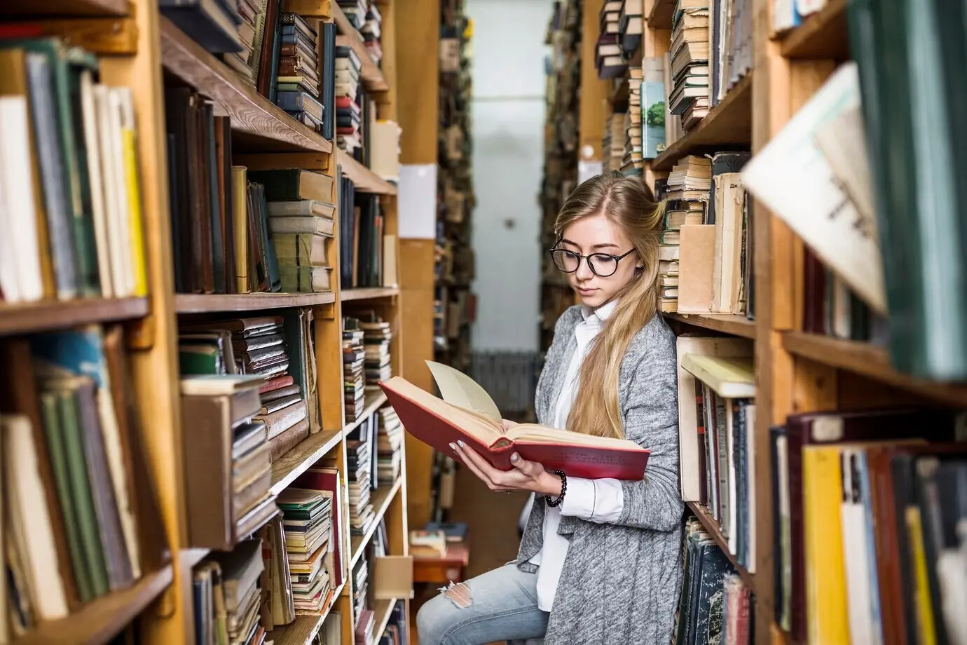 Student liest ein Buch zwischen Bücherregalen.